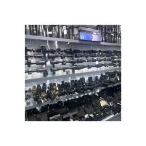 A retail display shelf featuring various black tactical rifle scopes, red dot sights, and precision optics for hunting and sports shooting